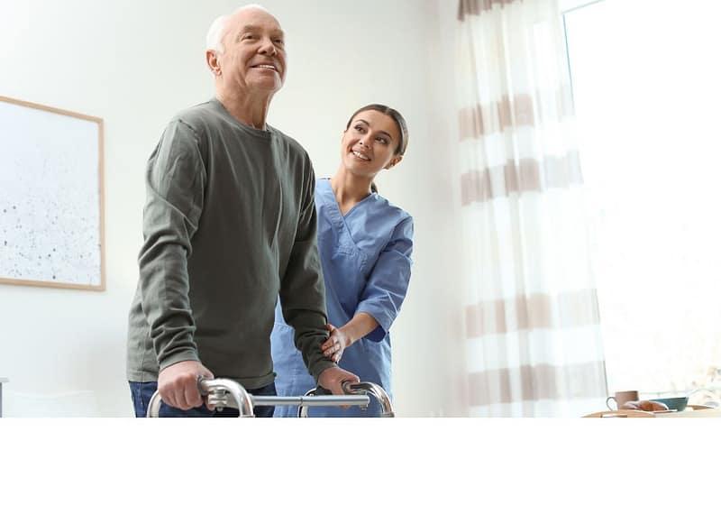 Healthcare worker helping an elderly patient to walk using walker